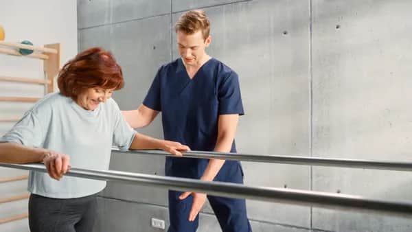 Sport-Physiotherapie-Spezialist-Dehnung-Muskel-Gruppen-mit-älter-Frau-Rehabilitation